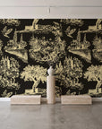 Inked Grove Gilt pastoral toile wallpaper behind a travertine pedestal and vase in a minimal boutique