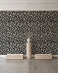 Khaki Leaf Charcoal botanical leaf wallpaper behind a travertine pedestal and vase in a minimal boutique