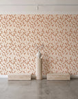 Khaki Leaf Clay botanical leaf wallpaper behind a travertine pedestal and vase in a minimal boutique