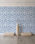 Khaki Leaf Indigo botanical leaf wallpaper behind a travertine pedestal and vase in a minimal boutique