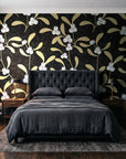 Mistletoe Trail Noir mistletoe wallpaper behind a tufted headboard in a dark, moody bedroom