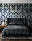 Misty Fern Romance Midnight damask wallpaper behind a tufted headboard in a dark, moody bedroom
