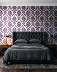 Misty Fern Romance Plum damask wallpaper behind a tufted headboard in a dark, moody bedroom