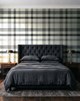 Moors & Mist Charcoal plaid wallpaper behind a tufted headboard in a dark, moody bedroom