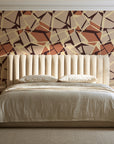 Muted Block Terracotta geometric wallpaper behind a channel-tufted bed in a calm primary bedroom