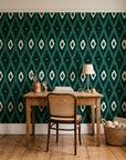Ogee Loom Emerald ikat ogee wallpaper behind a vintage writing desk in a cozy craft-room home office