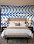 Ogee Loom Indigo ikat ogee wallpaper behind the headboard of a king bed in a contemporary hotel guest room