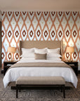 Ogee Loom Terracotta ikat ogee wallpaper behind the headboard of a king bed in a contemporary hotel guest room
