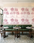 Palm Shade Rose palm grove wallpaper above a green leather banquette in a sunlit neighborhood cafe