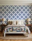 Pastel Bouquet Parade Navy botanical damask wallpaper behind a white cottage bed with a patchwork quilt in a cozy cottagecore bedroom