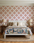 Pastel Bouquet Parade Terracotta botanical damask wallpaper behind a white cottage bed with a patchwork quilt in a cozy cottagecore bedroom