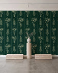 Petal & Thread Emerald botanical stem wallpaper behind a travertine pedestal and vase in a minimal boutique