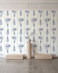 Petal & Thread Indigo botanical stem wallpaper behind a travertine pedestal and vase in a minimal boutique