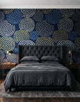 Petal Cascade Midnight spiral rosette wallpaper behind a tufted headboard in a dark, moody bedroom