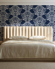 Petal Symphony Navy baroque damask wallpaper behind a channel-tufted bed in a calm primary bedroom
