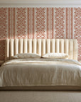 Porcelain Filigree Terracotta filigree damask wallpaper behind a channel-tufted bed in a calm primary bedroom