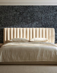 Quiet Camo Charcoal abstract wallpaper behind a channel-tufted bed in a calm primary bedroom