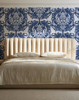 Serene Blossom Indigo damask wallpaper behind a channel-tufted bed in a calm primary bedroom