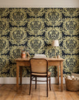 Serene Blossom Noir damask wallpaper behind a vintage writing desk in a cozy craft-room home office