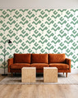 Signal & Edge Sage geometric wallpaper behind a rust velvet sofa in a bright coworking lounge