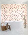 Sketched Seashells Coral seashell wallpaper behind a freestanding tub in a bright coastal bathroom