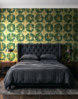 Solar Ritual Emerald floral wallpaper behind a tufted headboard in a dark, moody bedroom