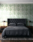Solar Ritual Sage floral wallpaper behind a tufted headboard in a dark, moody bedroom