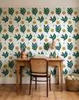 Spice & Frond Emerald leaf frond wallpaper behind a vintage writing desk in a cozy craft-room home office