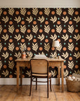 Spice & Frond Espresso leaf frond wallpaper behind a vintage writing desk in a cozy craft-room home office