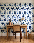 Spice & Frond Indigo leaf frond wallpaper behind a vintage writing desk in a cozy craft-room home office