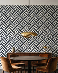Still Labyrinth Ink maze geometric wallpaper behind a walnut credenza and round table in an elegant dining room