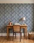 Still Labyrinth Ink maze geometric wallpaper behind a vintage writing desk in a cozy craft-room home office