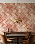 Still Labyrinth Terracotta maze geometric wallpaper behind a walnut credenza and round table in an elegant dining room