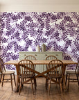 Still Morning Plum foliage wallpaper in a farmhouse dining room with a sage sideboard and rustic trestle table