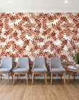 Still Morning Terracotta foliage wallpaper behind a row of upholstered chairs in a bright clinic waiting room