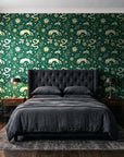 Sun & Moon Emerald celestial folk wallpaper behind a tufted headboard in a dark, moody bedroom