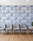 Tranquil Flora Indigo floral damask wallpaper behind a row of upholstered chairs in a bright clinic waiting room