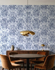 Tranquil Flora Indigo floral damask wallpaper behind a walnut credenza and round table in an elegant dining room
