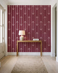 Tranquility Tapestry Oxblood art deco stripe wallpaper behind a console table in a light entry hallway
