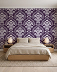 Veiled Botany Plum damask wallpaper behind a low platform bed in a serene Japandi bedroom