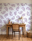 Verdant Scatter Plum tossed leaf wallpaper behind a vintage writing desk in a cozy craft-room home office