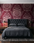 Vintage Eden Oxblood damask wallpaper behind a tufted headboard in a dark, moody bedroom