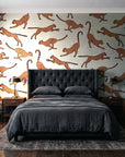 Wild Stride Terracotta cheetah wallpaper behind a tufted headboard in a dark, moody bedroom