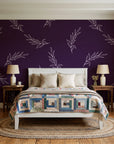 Willow Whisper Aubergine willow sprig wallpaper behind a white cottage bed with a patchwork quilt in a cozy cottagecore bedroom