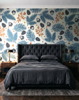 Winter Forage Slate pine bough and berry wallpaper behind a tufted headboard in a dark, moody bedroom
