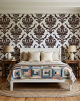 Woodland Blossom Veil Espresso damask wallpaper behind a white cottage bed with a patchwork quilt in a cozy cottagecore bedroom