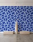 Woven Whisper Cobalt abstract heart wallpaper behind a travertine pedestal and vase in a minimal boutique