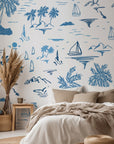 Coastal illustrated wallpaper displayed on a living room accent wall with palm tree and sailboat sketches creating a calm seaside atmosphere.