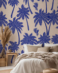 Tropical palm wallpaper featured on a bedroom wall, creating a relaxed coastal interior with bold blue palm silhouettes.