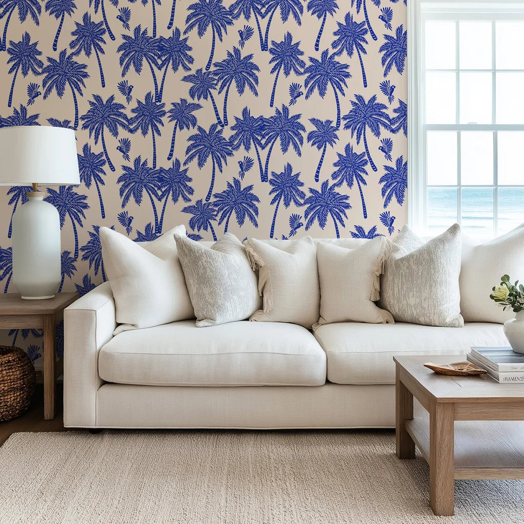Blue palm wallpaper used as a living room accent wall, bringing a resort style feel with repeating palm trees and birds.